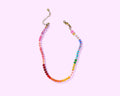 Colorful beaded necklace on a light pink background